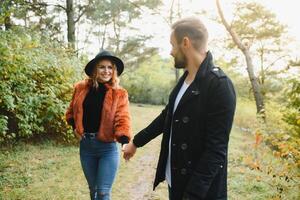 Young couple in love walking in the autumn park holding hands looking in the sunset. photo