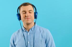 Handsome young man listening to music on color background photo