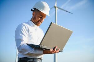 Engineer standing and hoding laptop with wind turbine. photo
