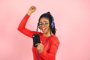 african american girl in headphones on a pink background. photo