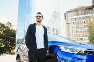 hermoso joven hombre en en pie cerca coche al aire libre foto