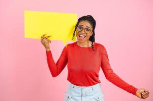 yo pensar. pensativo afro mujer mirando a blanco habla burbuja, conmovedor su mentón, espacio de copia, rosado estudio pared. foto