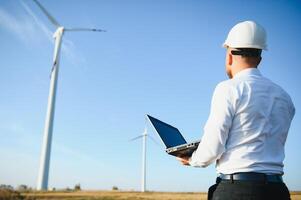 Engineer standing and hoding laptop with wind turbine. photo