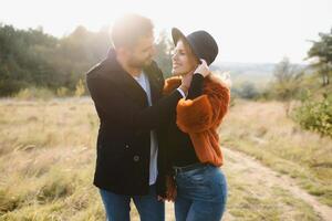 Young couple in love walking in the autumn park holding hands looking in the sunset. photo