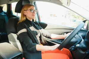 Beautiful mature woman in business suit driving a car to office. Businesswoman drive a car in city. photo