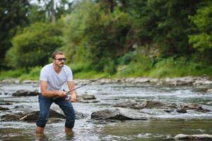 Bearded man catching fish. Summer leisure. Mature man fishing on the pond. Portrait of cheerful senior man fishing. Male fishing. Fishman crocheted spin into the river waiting big fish photo