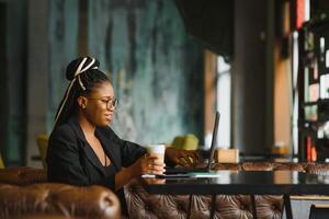 Young African American woman siting at cafe working on laptop photo