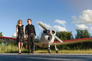retrato de dos sonriente negocio gente, hombre y mujer, caminando por avión hangar en aeropuerto campo foto
