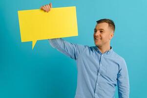 guy holding speech bubble on blue studio background, mockup for design photo