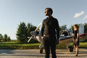 Young handsome businessman is standing near private plane. Confident and successful man in airport. photo