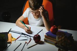 Boy learn lessons in the home setting at the table in the light of a table lamp. photo