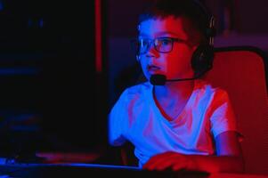 Little boy playing video game in the dark room photo