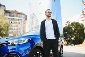 hermoso joven hombre en en pie cerca coche al aire libre foto