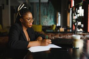 Young African American woman siting at cafe working on laptop photo