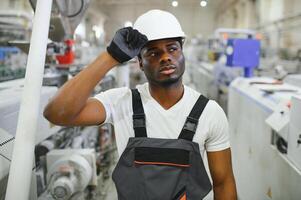 Portrait of industrial engineer. Smiling factory worker with hard hat standing in factory production line photo