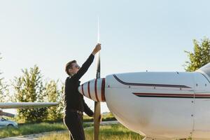 Pensive attrative young man pilot standing near small aircraft photo