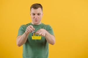 Shocked young man posing isolated on yellow orange background, studio portrait. People emotions lifestyle concept. Mock up copy space. Holding in hand car keys, showing thumb up photo