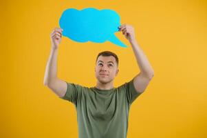 Young caucasian man isolated on yellow background holding a thinking speech bubble and doing OK sign photo