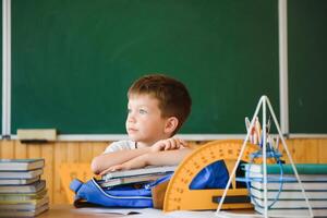 Education and learning. Little schoolboy in classroom. Schoolboy doing homework in classroom at school. Elementary school kid sitting at desk. Education. Kid at school. photo