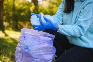 hand puts plastic debris in the garbage bag in the park photo