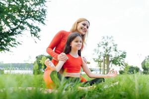 madre y hija haciendo yoga ejercicios en césped en el parque a el día hora foto