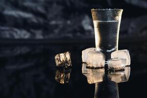 Close-up view of bottle and glasses of vodka standing isolated on black. photo