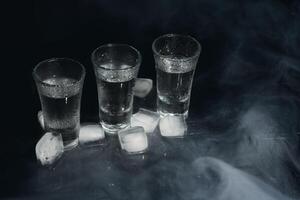 Vodka. Shots, glasses with vodka with ice .Dark background. Copy space .Selective focus. photo