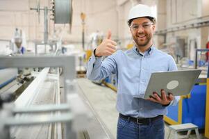 Side view of technician or engineer with headset and laptop standing in industrial factory photo