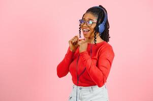 african american girl in headphones on a pink background. photo