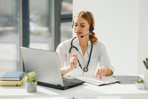 médico hablando con enfermo persona mediante ordenador portátil en línea sistema y utilizando móvil digital tableta computadora buscando paciente médico registros en el base de datos archivos documento foto