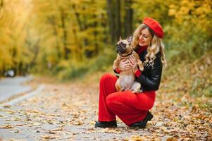 People and dogs outdoors. Beautiful and happy woman enjoying in autumn park walking with her adorable French bulldog. photo