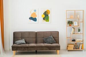 Painting on white wall above sofa with cushions in living room interior photo