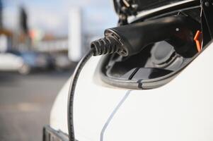 Power supply for electric car charging. Electric car charging station. Close up of the power supply plugged into an electric car being charged. photo