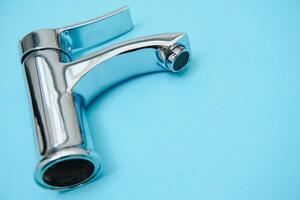Single handle water tap on light blue background, closeup photo