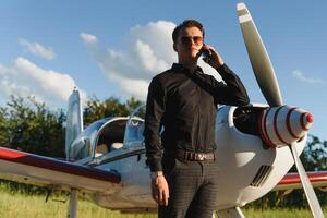 joven hermoso empresario es en pie cerca privado avión. confidente y exitoso hombre en aeropuerto. foto