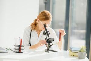 médico mujer trabajando un microscopio. hembra científico mirando mediante un microscopio en laboratorio. estudiante mirando en un microscopio, Ciencias laboratorio concepto foto