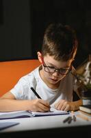 Boy learn lessons in the home setting at the table in the light of a table lamp. photo