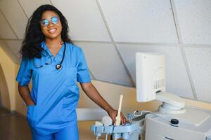 bonito hembra africano médico con brazos cruzado a hospital foto