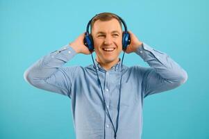 Handsome young man listening to music on color background photo