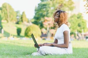 A young female african-american woman working on her laptop computer, enjoying a day at the park photo