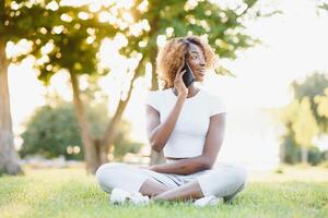 people, technology and leisure concept - happy african american young woman calling on smartphone outdoors photo