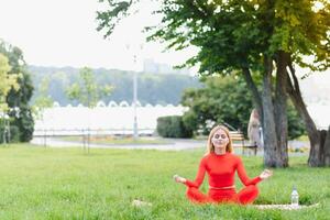 Young woman doing yoga exercise in green park photo