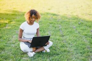 A young female african-american woman working on her laptop computer, enjoying a day at the park photo