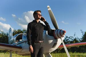 handsome businessman near private jet. Successful man at the airport talking on the phone. photo