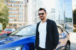 hermoso joven hombre en en pie cerca coche al aire libre foto