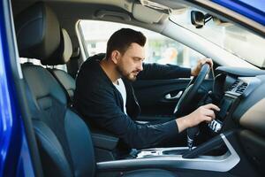 Test drive for auto. Pleasant overjoyed handsome boy holding steering wheel and driving his car while expressing gladness photo