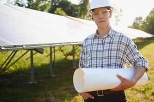 The portrait of a young engineer checks photovoltaic solar panels. Concept renewable energy, technology, electricity, service, green power. photo