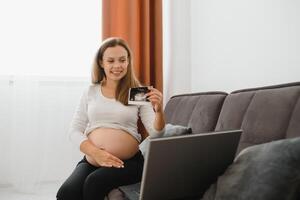 Pregnant woman video chatting with doctor on laptop. Professional medical online consultation concept. photo