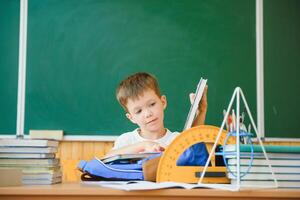 Education and learning. Little schoolboy in classroom. Schoolboy doing homework in classroom at school. Elementary school kid sitting at desk. Education. Kid at school. photo