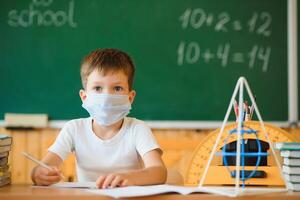 colegial en el salón de clases en un protector mascarilla. el concepto de enseñanza durante el epidemia foto